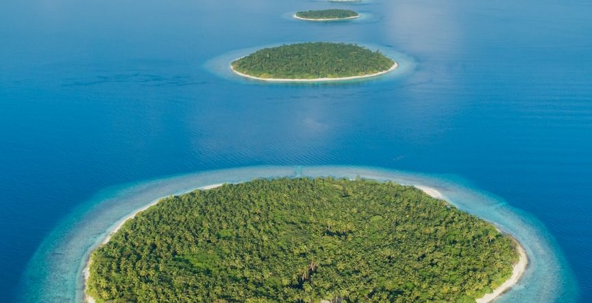 Drei grüne Inseln in einem blauem Meer mit klarem Wasser und weißen Sandstränden.