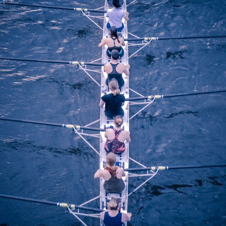 Eine Gruppe von Ruderern rudert synchron auf einem Gewässer.