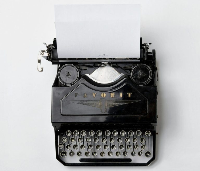 Schwarze Schreibmaschine mit leerem Blatt Papier.