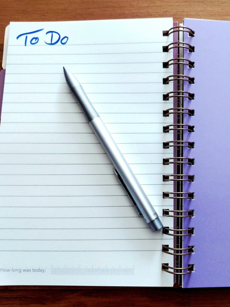 Notizbuch mit einer "To Do"-Liste und einem silbernen Stift darauf.